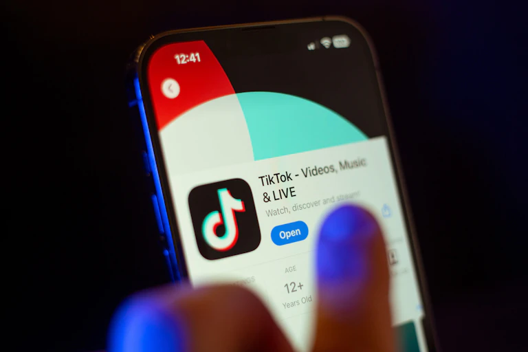 A hand on a phone with TikTok displayed.