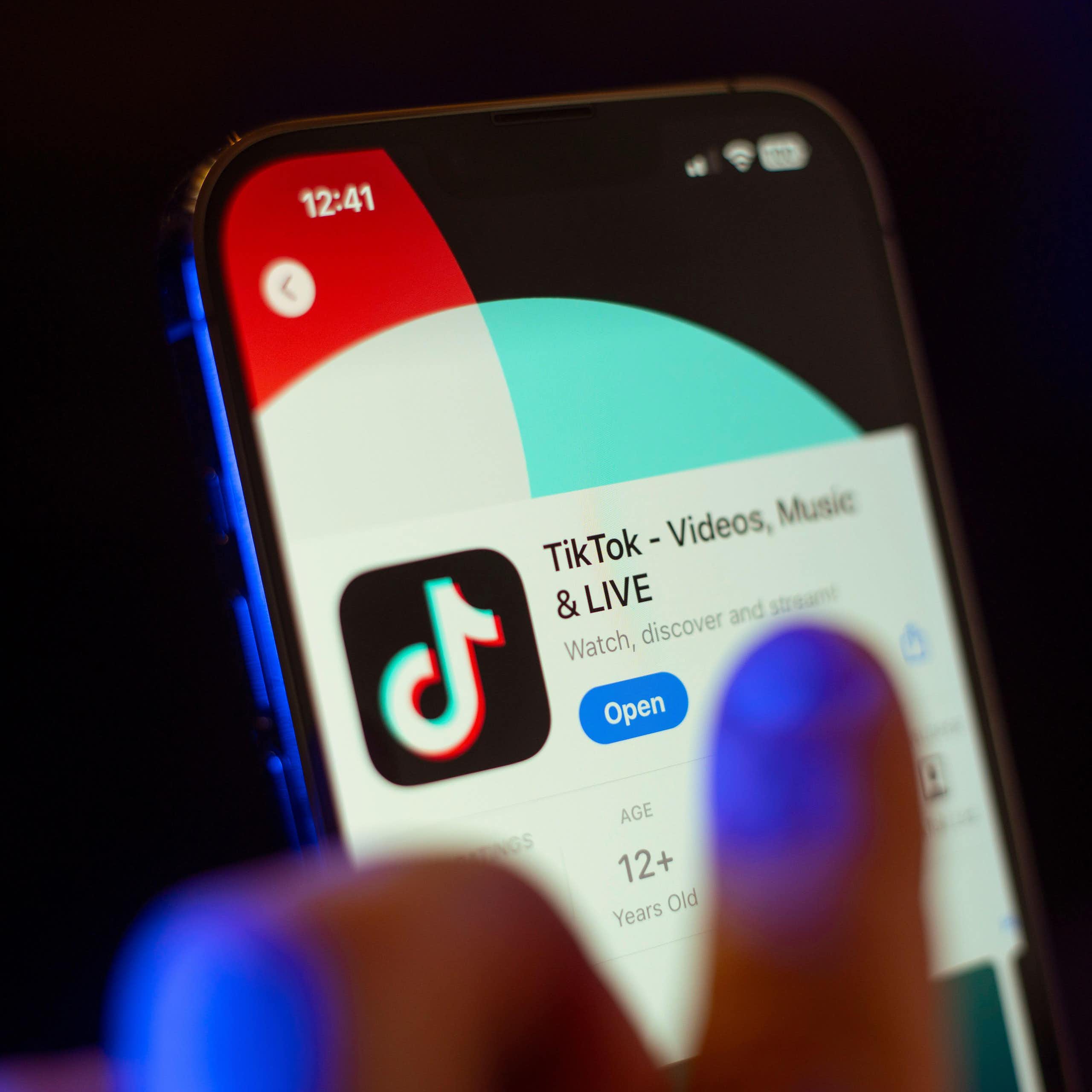 A hand on a phone with TikTok displayed.