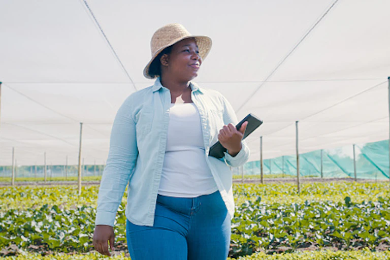 A woman stands in a crop field, smiling