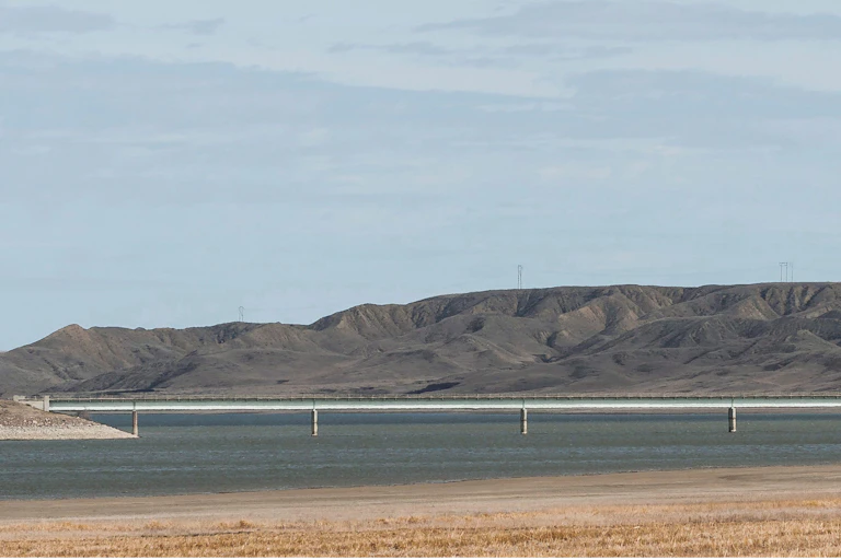 A bridge crosses a reservoir against a hilly backdrop.
