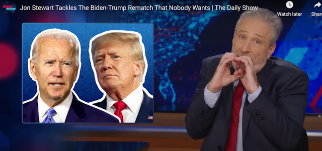 A man making a funny shape with his hands with photos of Donald Trump and Joe Biden on a screen next to him.