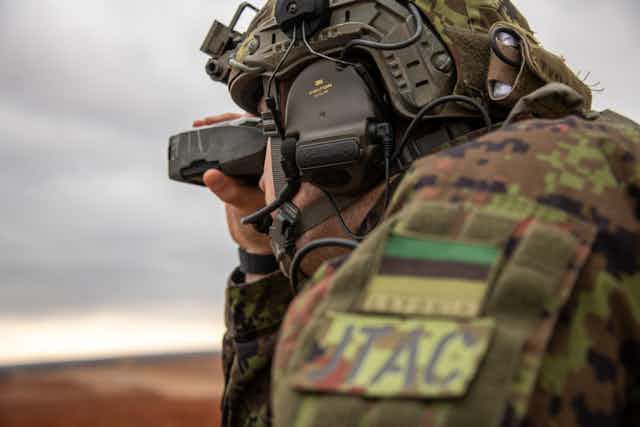 An Estonian tactical air control party specialist looks into the distance.