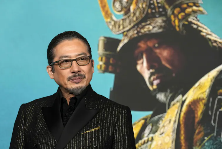 Japanese man wearing glasses and a suit.
