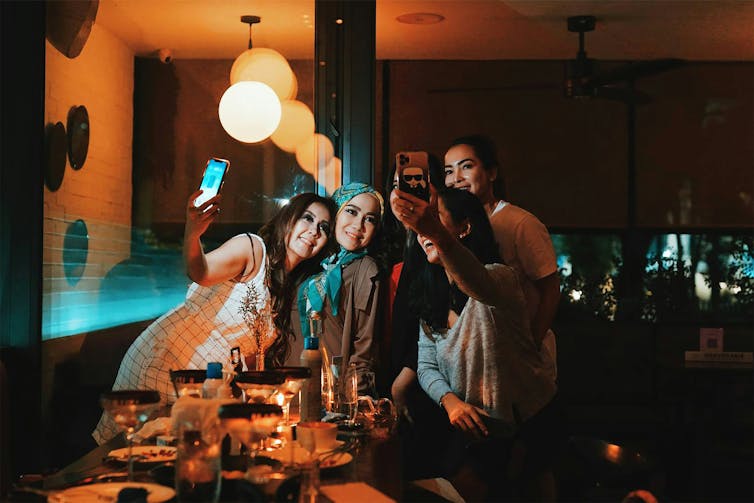 A group of women at a nice restaurant taking a selfie together.