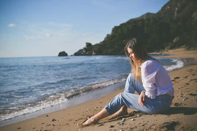 Woman sits on beach in the sun