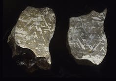 Two polished iron meteorites on a black background