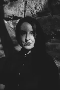woman with dark lipstick and long, dark hair, wearing black - a shadow over the left of her face