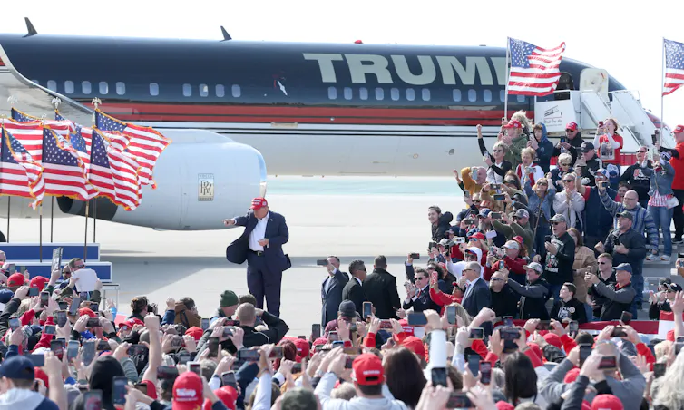 Fans taking pictures of Donald Trump in front of his personally branded plane.