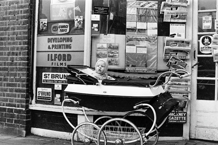 A baby in a pram in an archival black and white photograph.