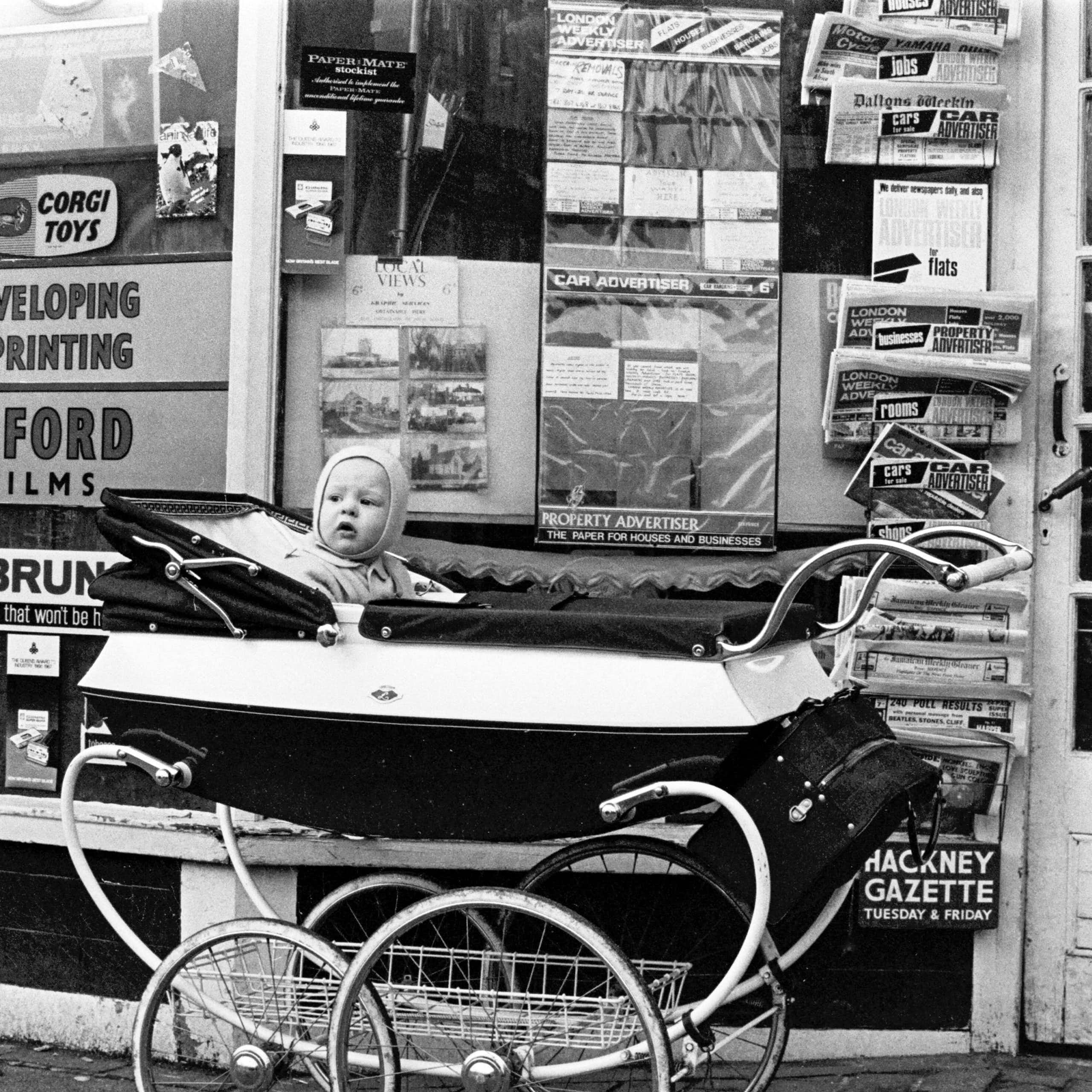 A baby in a pram in an archival black and white photograph.