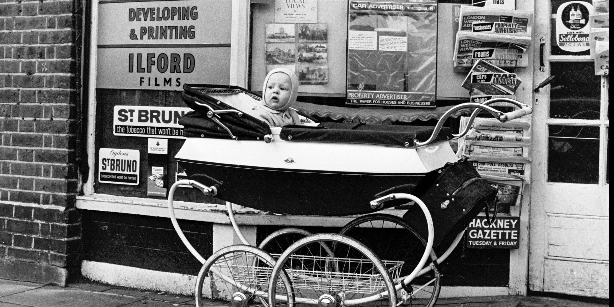 A baby in a pram in an archival black and white photograph.