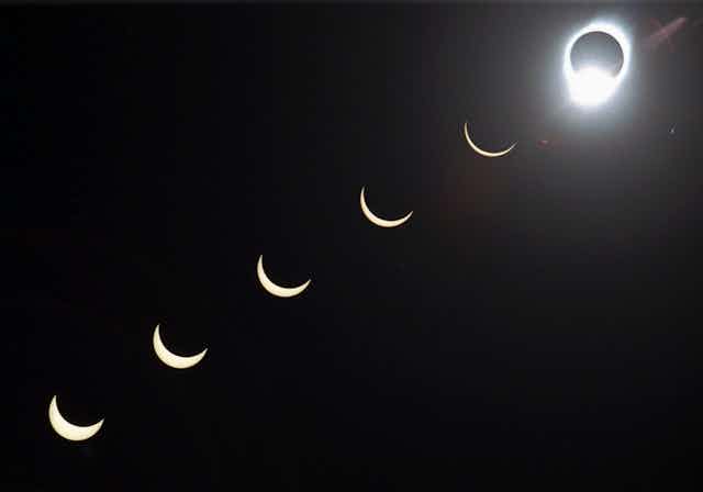 A solar eclipse, with the Moon covering the Sun with just an outline of light visible around it, in the top right, with varying stages of coverage moving from the bottom left to the right, as the sliver of Sun visible gets smaller. 