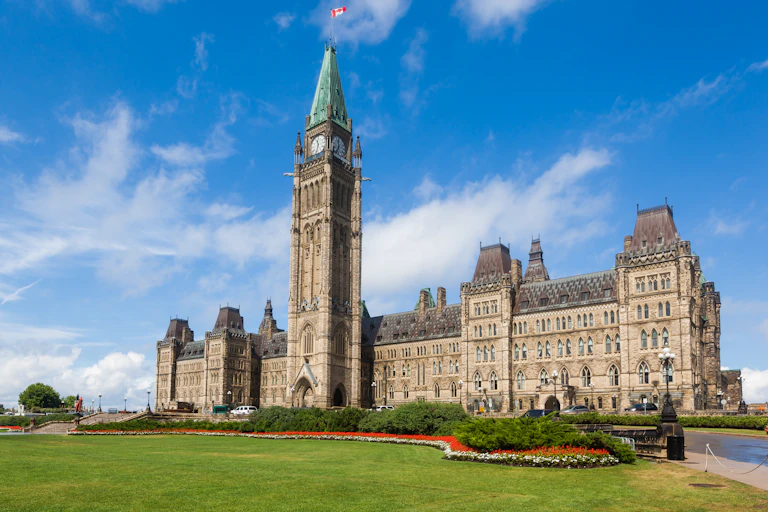 A large building with a green lawn and flowerbeds.
