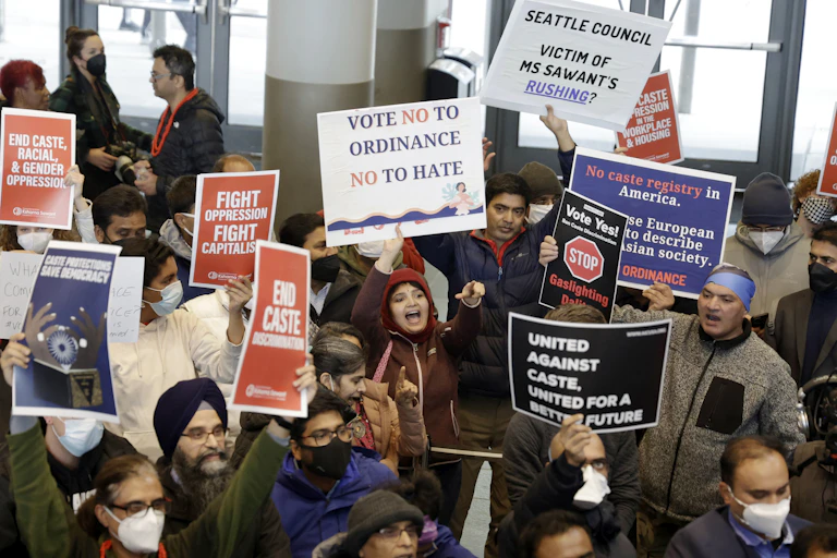 People carry signs at a protest about caste