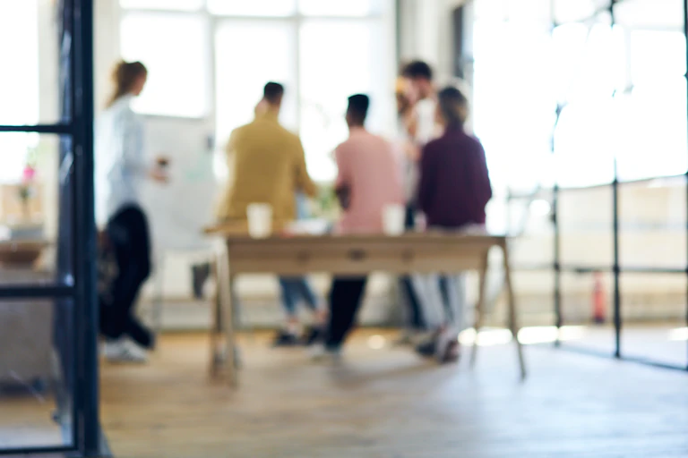 Une équipe de travail réunie autour d'une table. la photographie est floue.