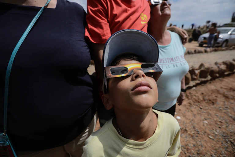 A young boy wearing protective glasses looks skyward.