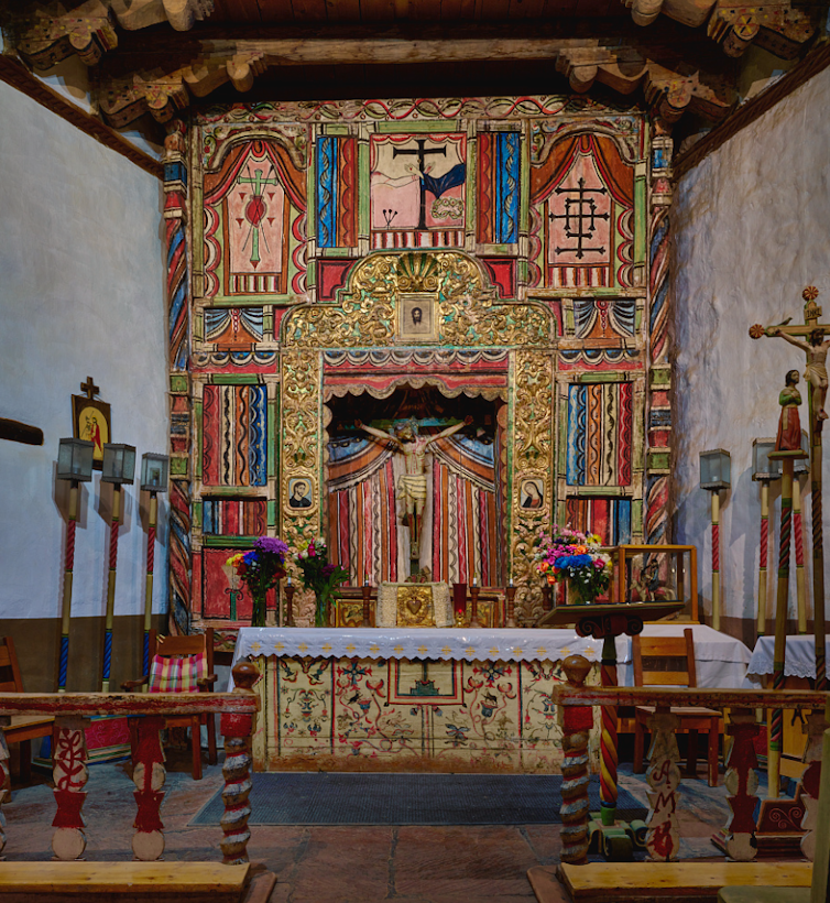 Um altar de igreja pintado em cores vivas com Jesus na cruz.