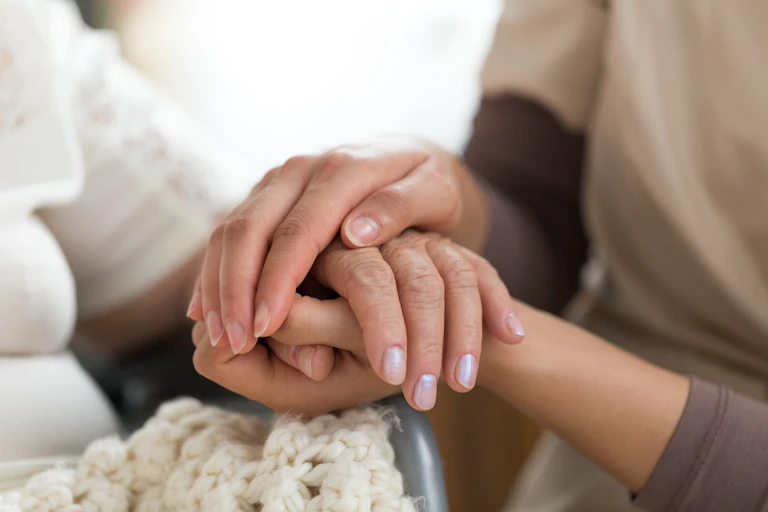 A close up of a young woman holding the hands of an older individual