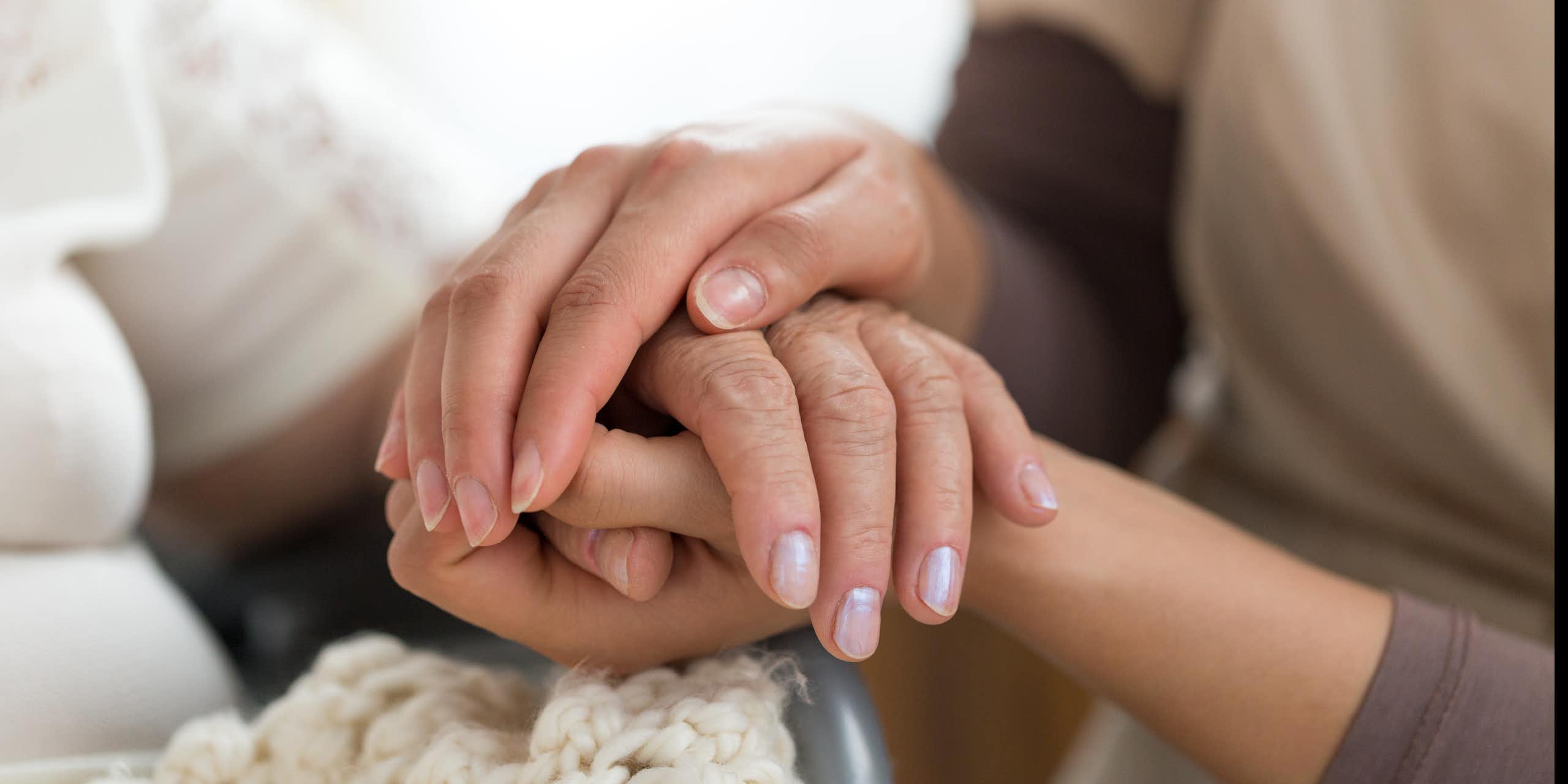 A close up of a young woman holding the hands of an older individual