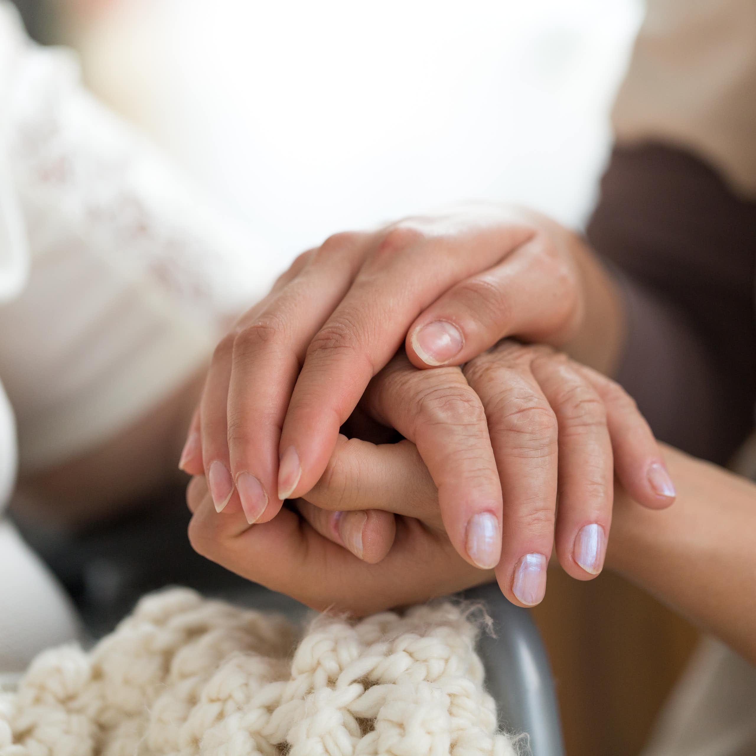 A close up of a young woman holding the hands of an older individual