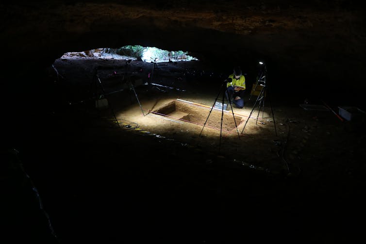 A dark cavern with a single light source illuminating a rectangular excavation.