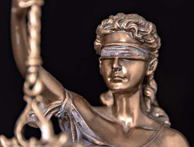 Close-up of a bronze figurine of Lady Justice wearing a blindfold.