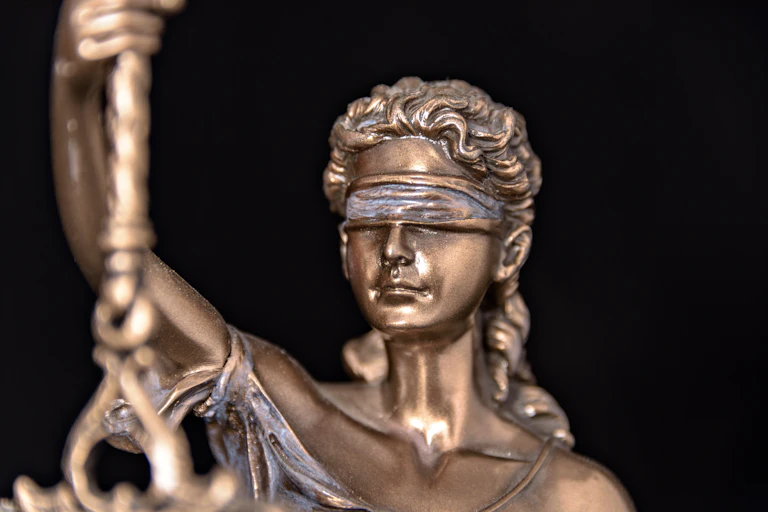 Close-up of a bronze figurine of Lady Justice wearing a blindfold.