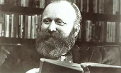 Portrait en noir et blanc d’un homme barbu tenant un livre
