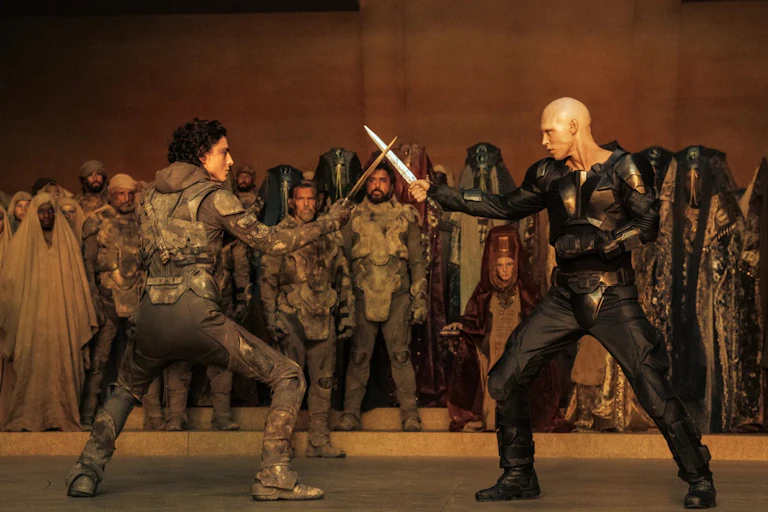 Scène de combat entre Paul Atréides et Feyd-Rautha Harkonnen dans Dune, deuxième partie. Les deux personnages croisent leurs dagues.