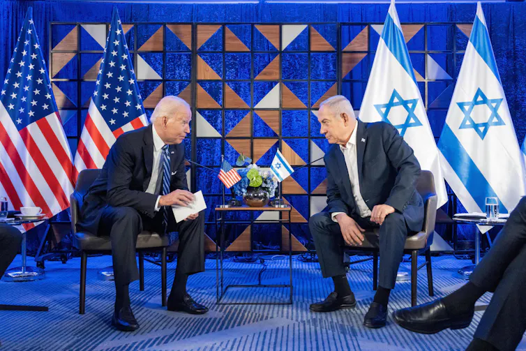 Biden and Netanyahu sit at a table, flags behind them