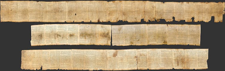 Three rows of yellowed manuscript on a scroll, with jagged edges.