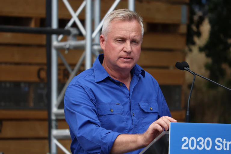 A man in a blue shirt speaking at a lectern