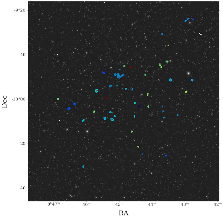 A photo of a field of stars with small loops of coloured lines.