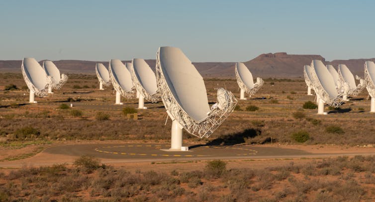 A photo of several large white radio dishes standing in a field.