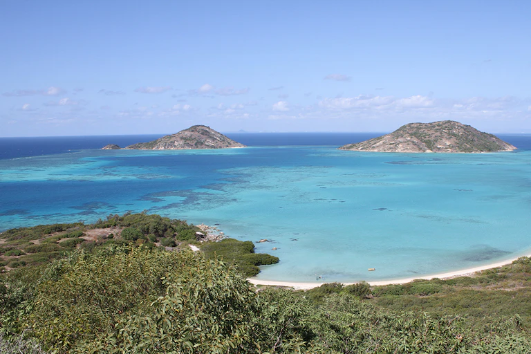 A photo of a shallow lagoon of blue water, fringed by green islands.