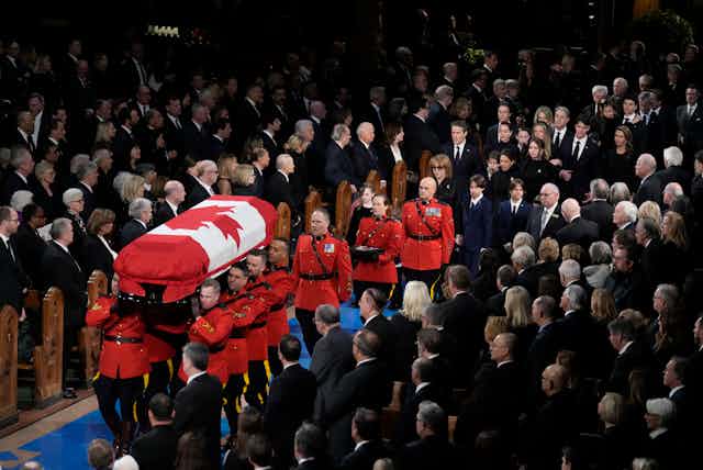 RCMP officers in their red tunics are watched by hundreds of people in the church.