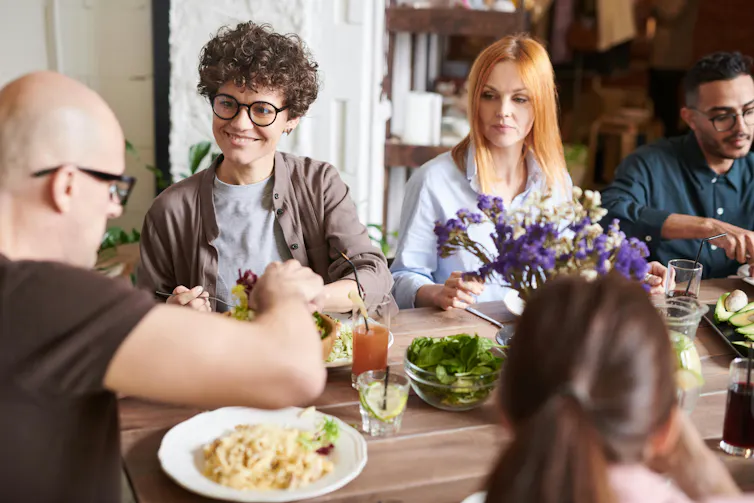 Um grupo de pessoas comendo ao redor de uma mesa.
