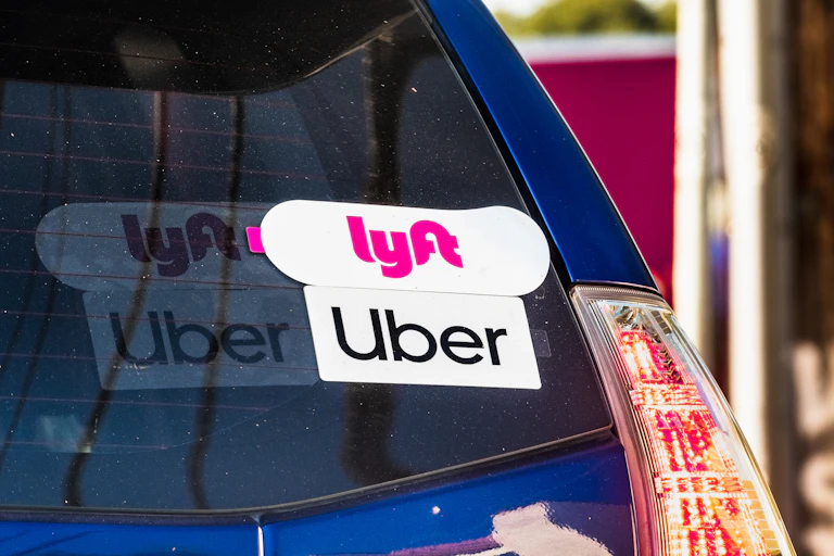 the back window of a car showing Uber and Lyft stickers