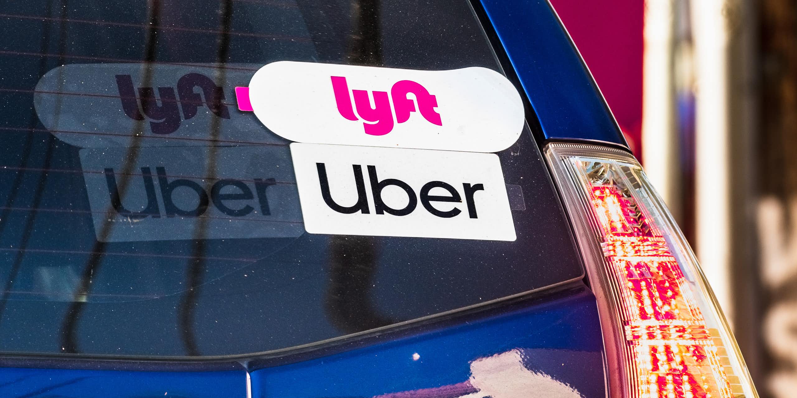 the back window of a car showing Uber and Lyft stickers
