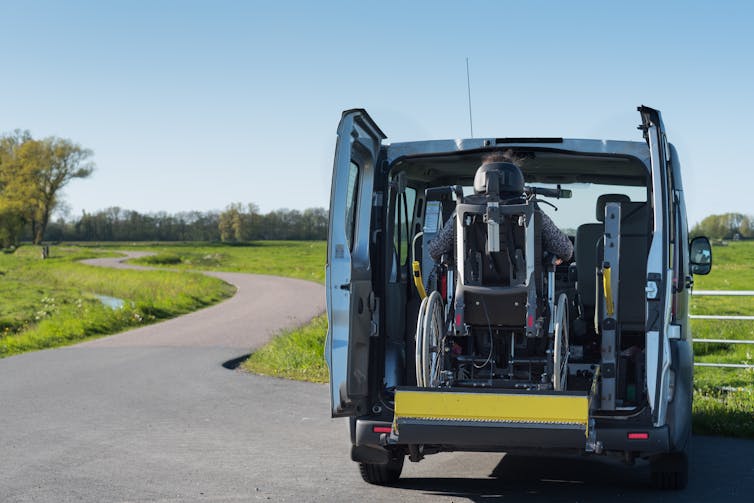 a wheelchair is being lifted through the rear doors of a van