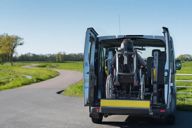 a wheelchair is being lifted through the rear doors of a van