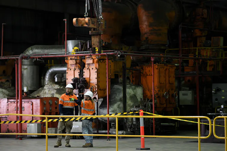 two coal plant workers in front of machinery