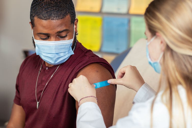 A health-care provider putting a bandage on a young man's arm