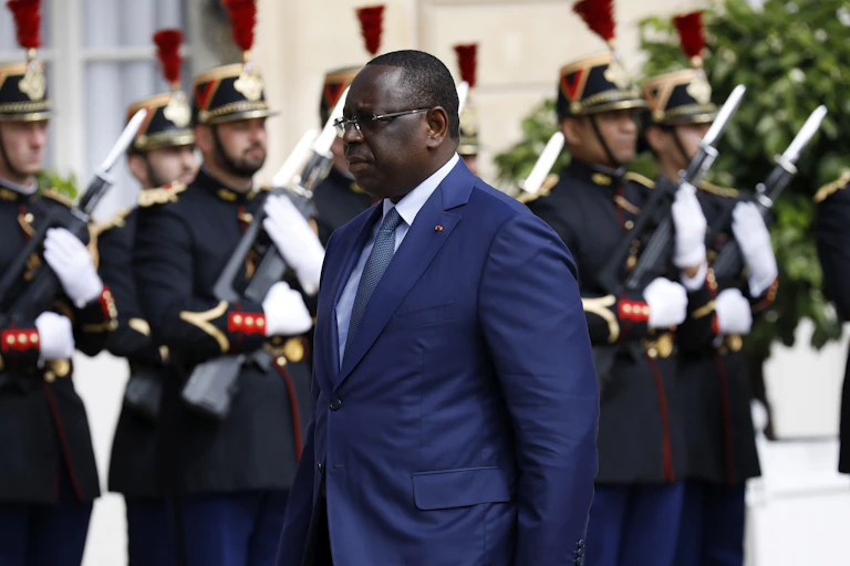 A man in blue suit walk pass a line of soldiers
