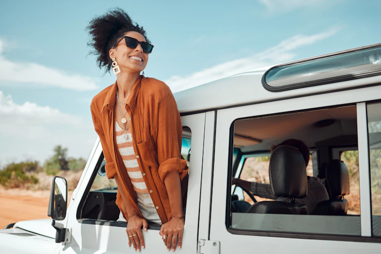 Woman leaning out of the window of a car with joyful expression