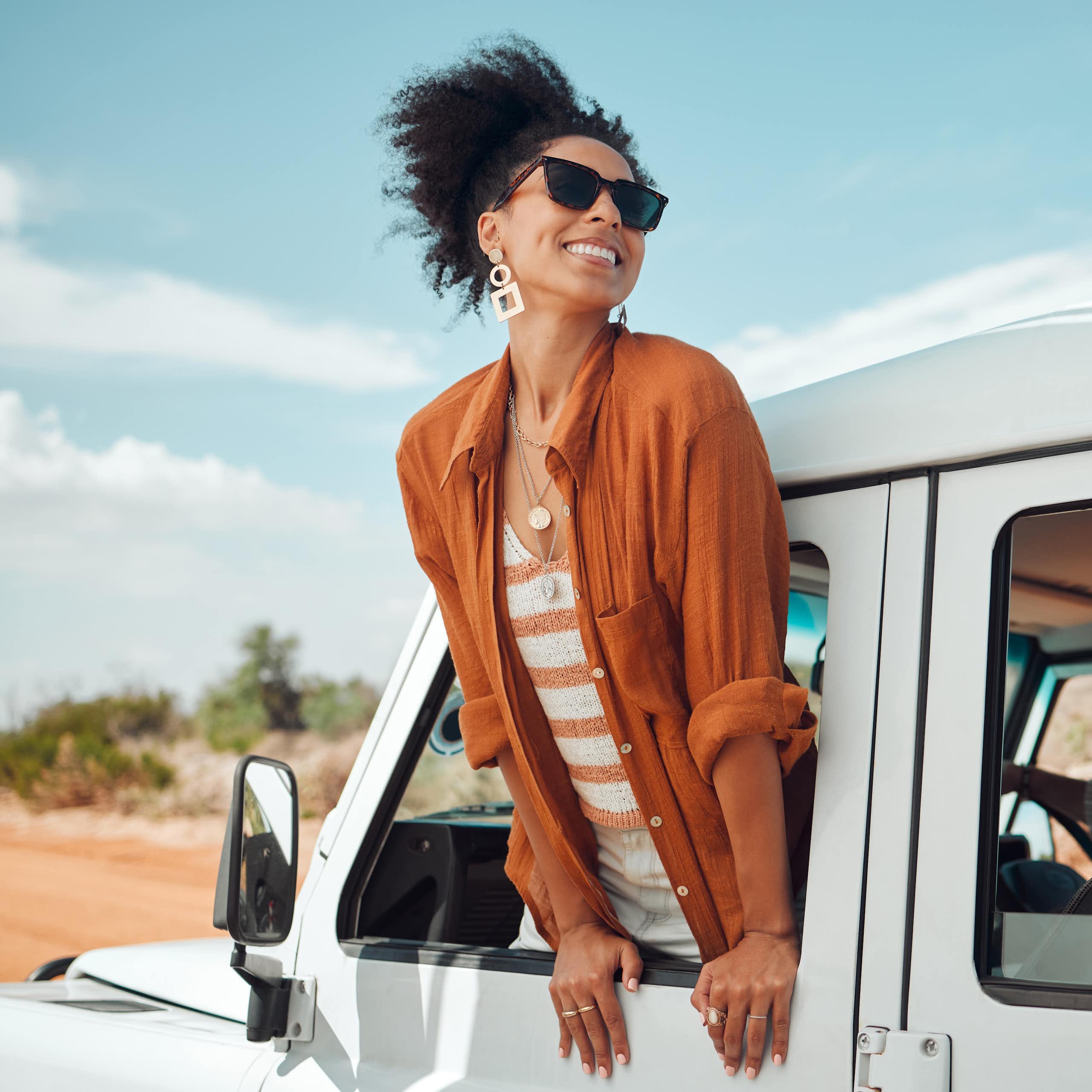 Woman leaning out of the window of a car with joyful expression