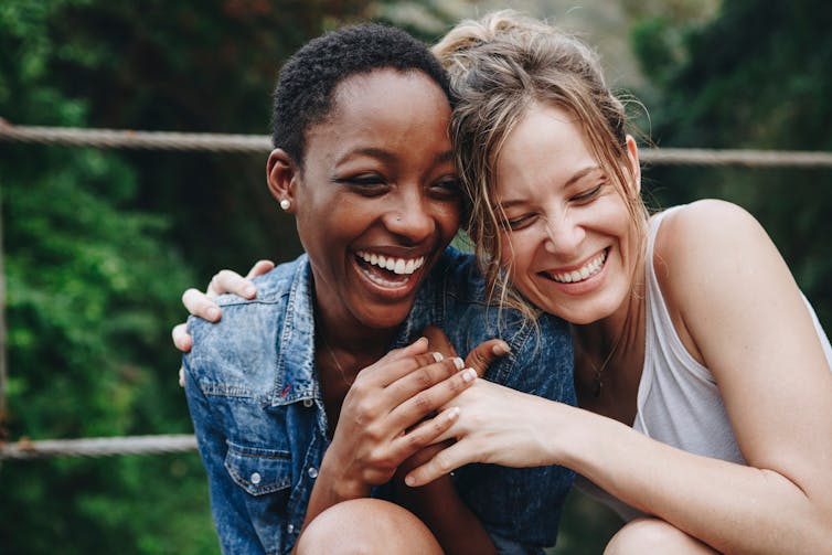 Two women hold each other with happy expression on their faces