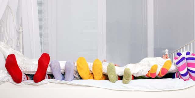 Diferentes tamaños de pies enfundados en calcetines en una cama