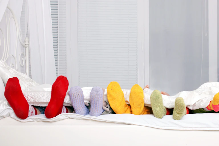 Diferentes tamaños de pies enfundados en calcetines en una cama