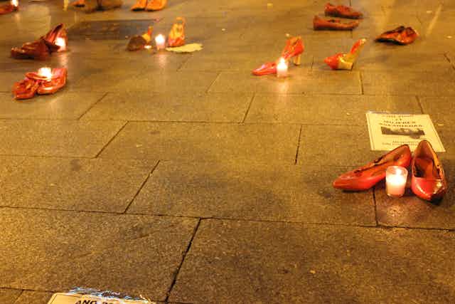 Zapatos rojos con velas en el suelo en señal de protesta.
